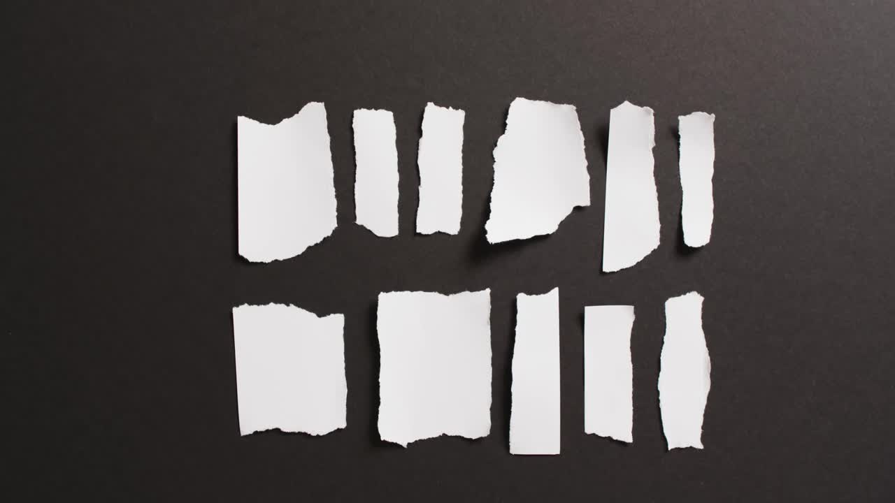 video de primer plano de varias piezas rasgadas de papel blanco sobre fondo negro