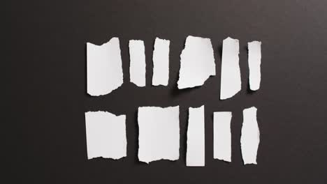 video of close up of multiple torn piece of white paper on black background