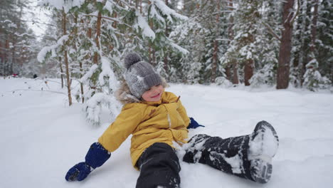 little child is wallowing in the snow and having fun in winter forest happy and carefree childhood