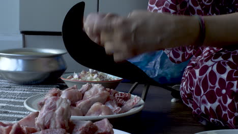 close-up hands of women slicing the raw chicken meat into small pieces on eid al-adha