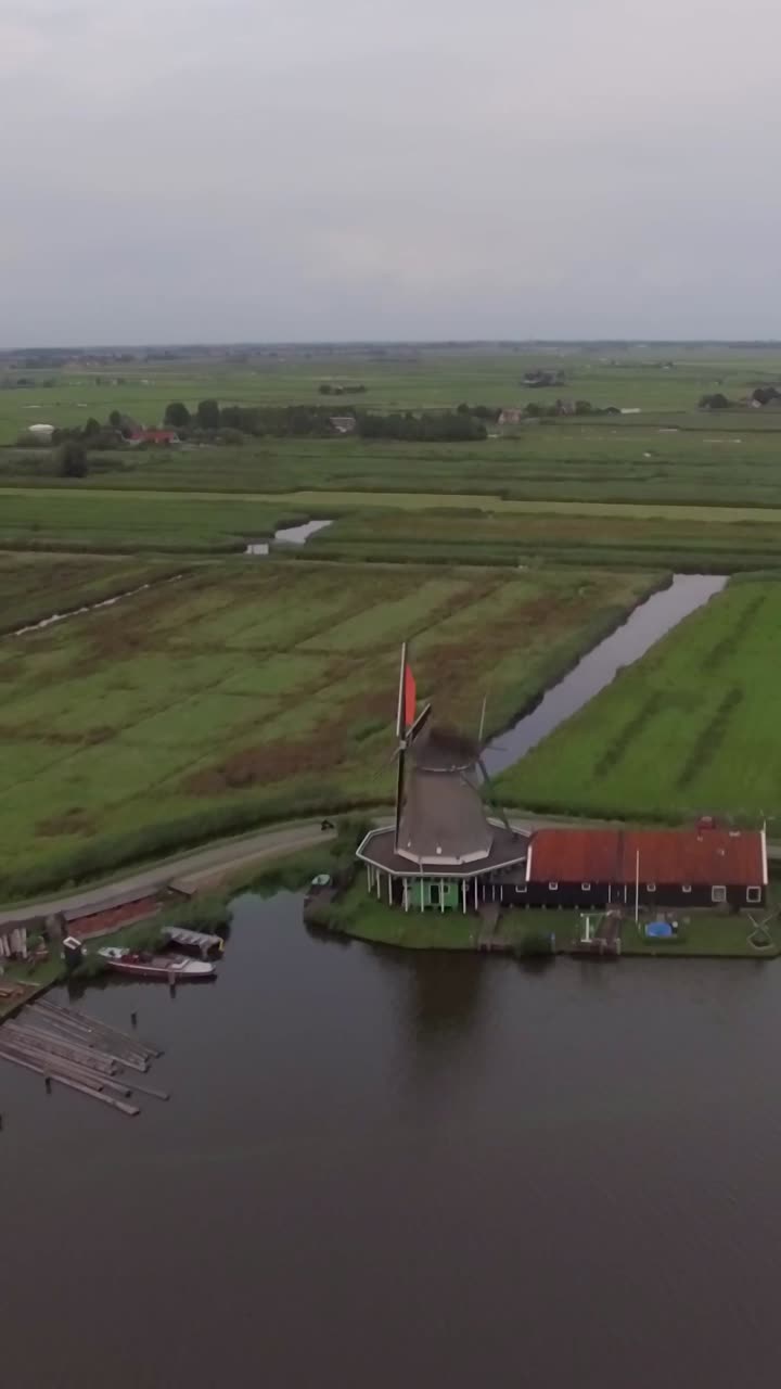 Veduta aerea di mulini a vento tradizionali e paesaggio di polder verdi nei Paesi Bassi.
