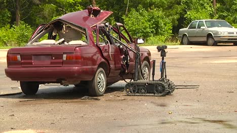 police and army troops use a remote control robot to diffuse a bomb in a car