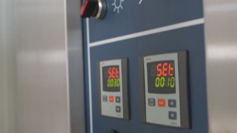 primer plano de manos masculinas ajustando la hora y la temperatura en el panel de control del horno de pan industrial