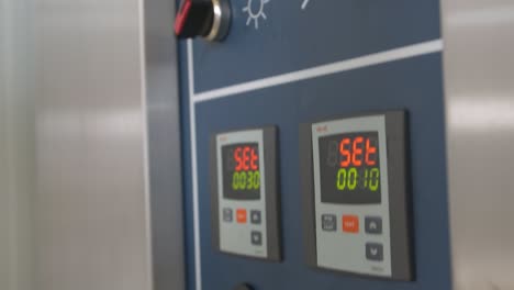 close-up of male hands setting time and temperature on the industrial bread oven control panel