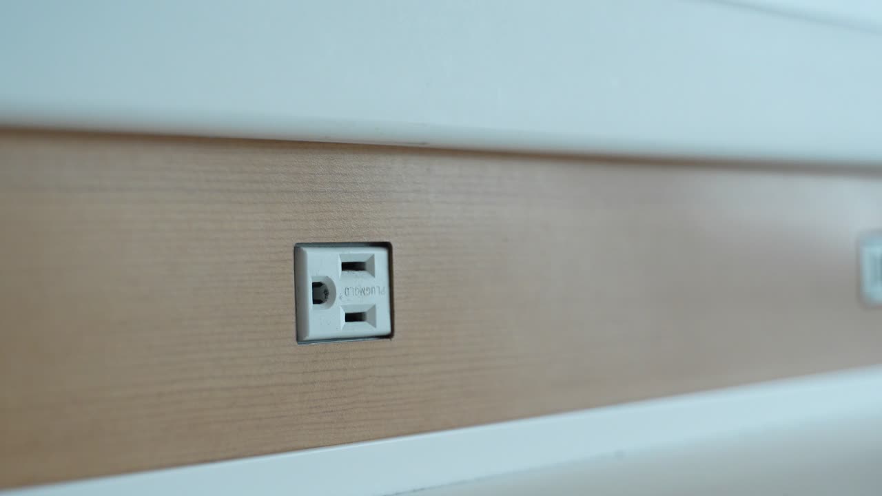 Plugging In iPhone Charger to Electrical Outlet Airport Desk