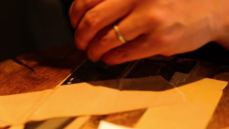 hands meticulously cutting paper with craft knife