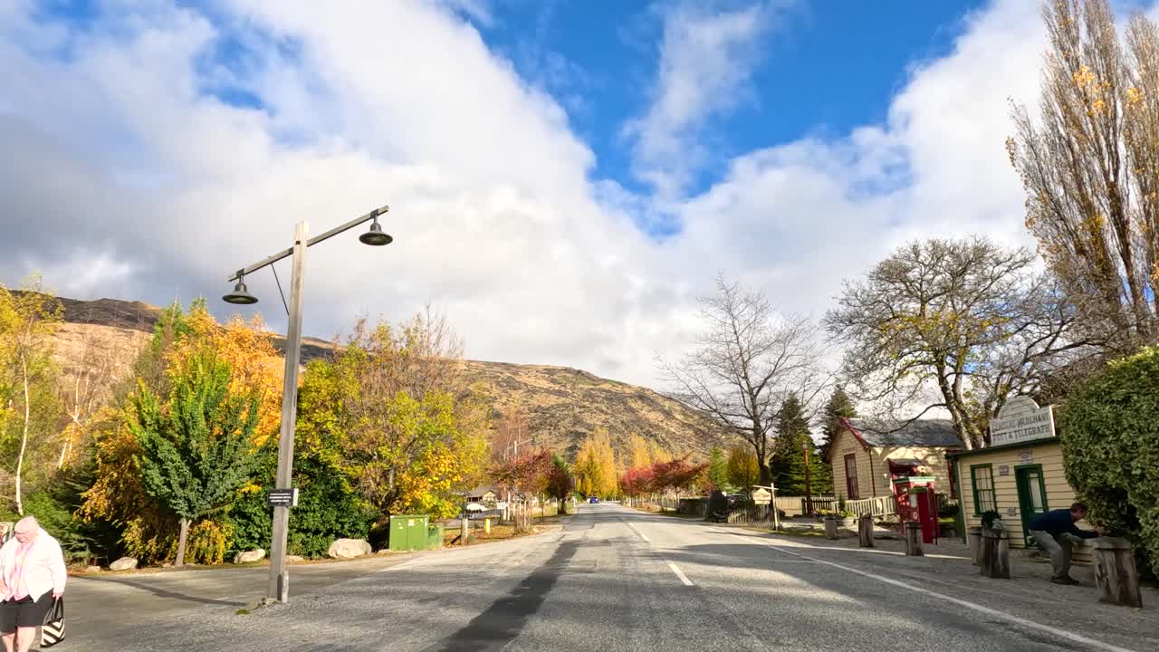 A picturesque drive through Wanaka's autumn landscape, showcasing vibrant foliage, clear skies, and serene roads