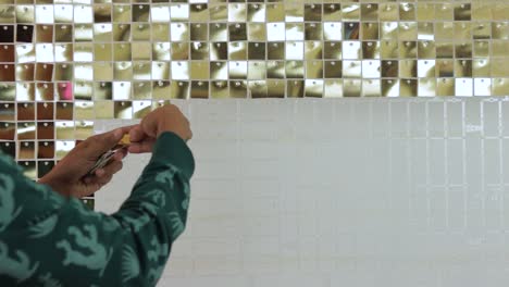 azulejos de vidrio de cristal con espejo de oro en una pared interior de la casa, decorados por una persona