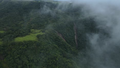 dense green jungle of costa rica with waterfall through misty cloud of fog, 4k drone