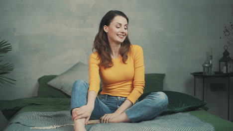 pretty smiling woman sitting on the bed at home and laughing