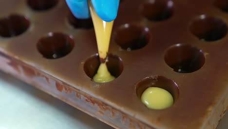 creamy stuffing squeezed into the molds covered with chocolate. manufacturing chocolate candies with white middles. close up.