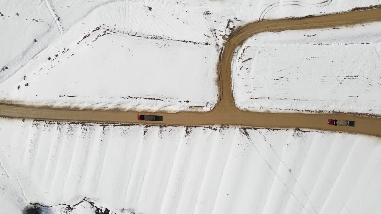 Trucks deliver cargo in difficult terrain in snowy winter, aerial tracking shot