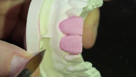 dental technician layering ceramic crown on central incisors precisely