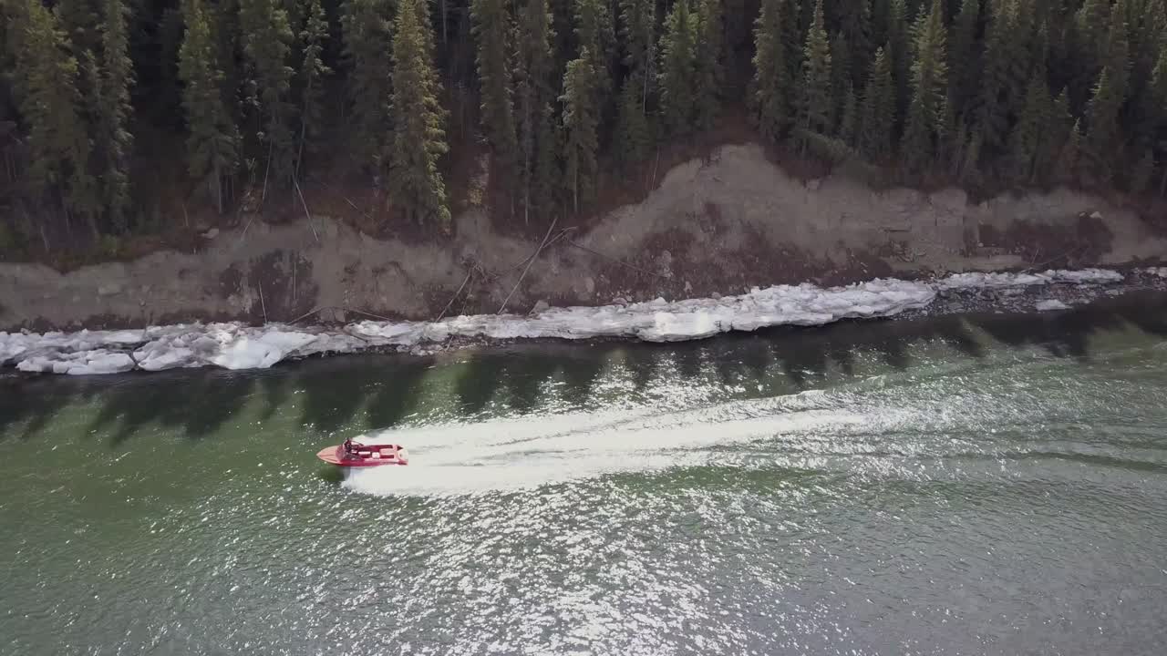 un barco navega por un río con hielo sucio a lo largo de sus orillas