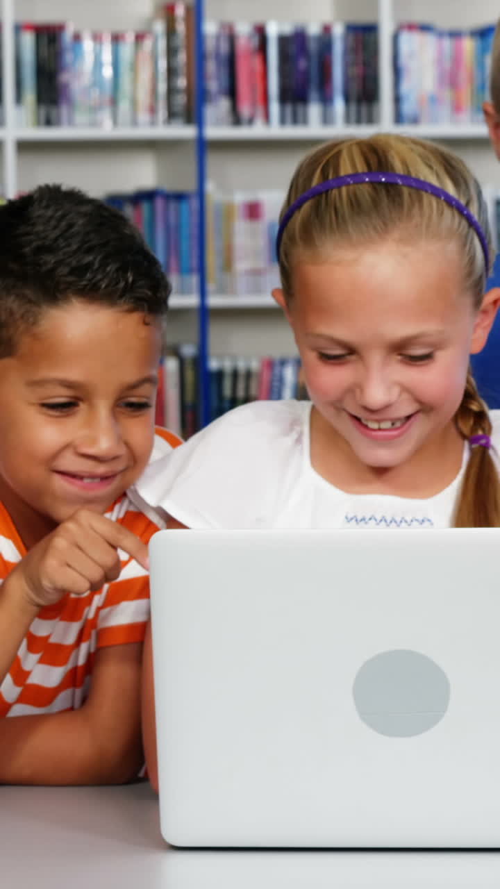 niños de la escuela usando computadora portátil en la biblioteca