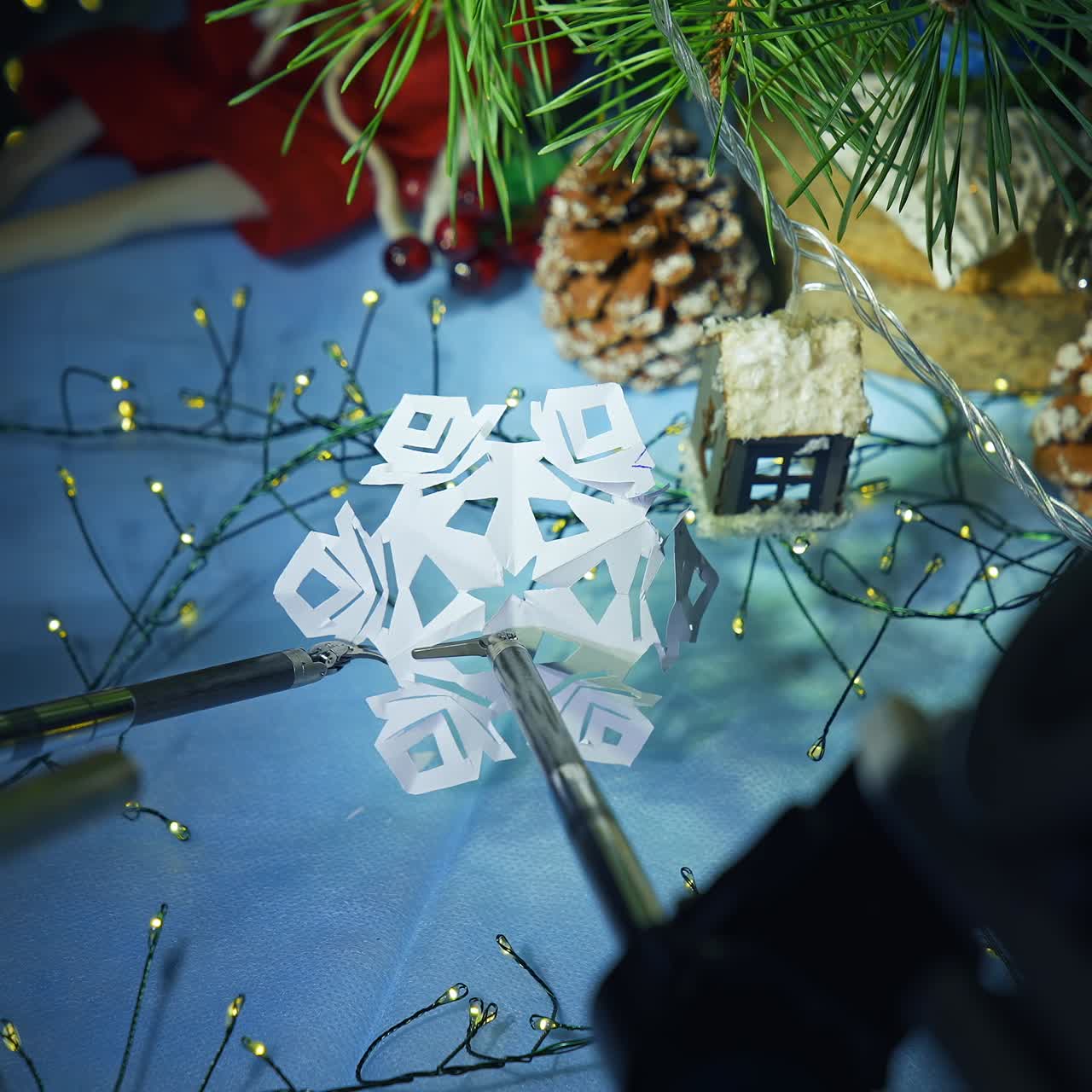 Robotic arms with tiny scissors and claw holding and cutting the paper snowflake. Da Vinci surgical system capabilities to sophisticated work. Close up