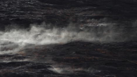 steam from volcano rolls off hardened magma rock for a dark and beautiful feeling