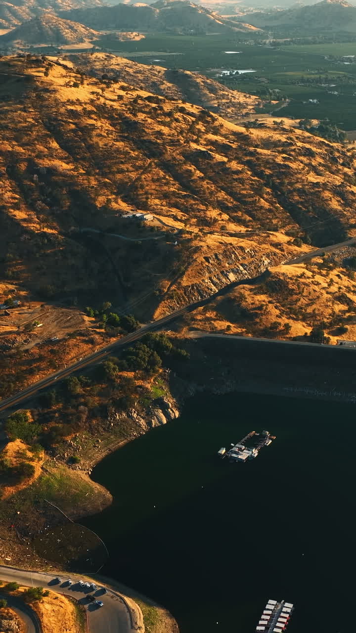 Flying above the lake in the mountains of California. Sunny green valleys at backdrop. View from aerial perspective. Vertical video