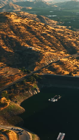 flying above the lake in the mountains of california. sunny green valleys at backdrop. view from aerial perspective. vertical video