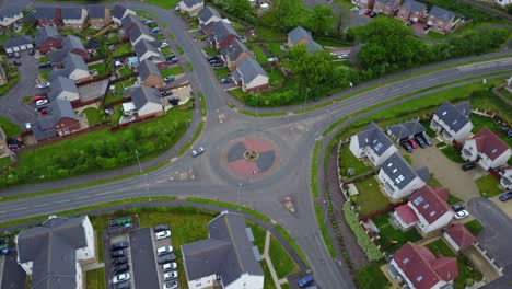 aerial video of a roundabout through cars circulate surrounded by buildings and some vegetation