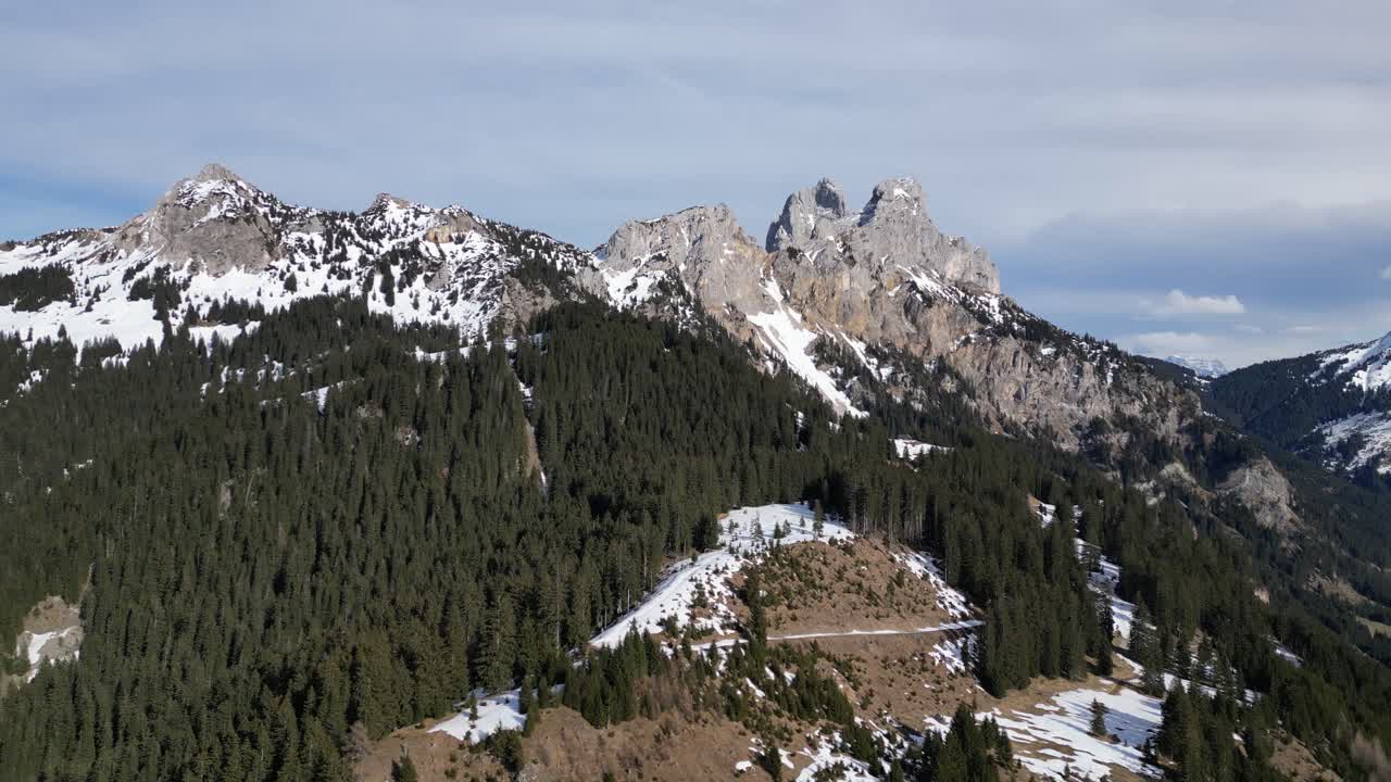 una foto aérea de los escarpados y pintorescos acantilados de la montaña de tirol-tannheim en suiza, donde los picos nevados se entrelazan con densos bosques, el atractivo natural del paisaje suizo