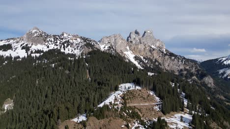 Aerial-of-the-rugged-and-picturesque-mountain-cliffs-of-Tirol-Tannheimer-Tal-in-Switzerland,-where-snow-capped-peaks-intertwine-with-dense-forests,-the-natural-allure-of-the-Swiss-landscape