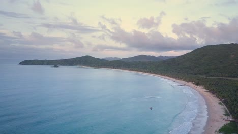 Aerial-lateral-tracking-shot-pan-right-of-long-beautiful-Nacpan-Beach-near-El-Nido-at-sunset-on-Palawan,-the-Philippines