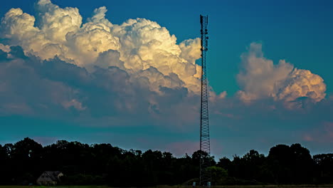 timelapse of big white clouds in the blue sky behind a communication tower