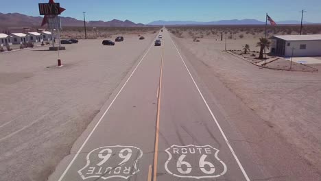 drone aerial over a lonely desert highway in arizona with route 66 painted on the pavement and car passing underneath 1