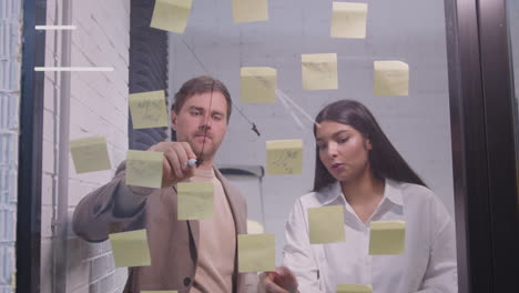 businessman and businesswoman brainstorming with sticky notes on glass window 1