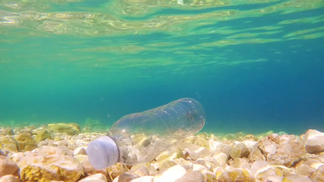 Una bottiglia di plastica galleggia sott'acqua. L'inquinamento marino impatta gli ecosistemi. La plastica monouso contribuisce ai problemi ambientali. Ridurre i rifiuti di plastica è importante per la salute degli oceani.