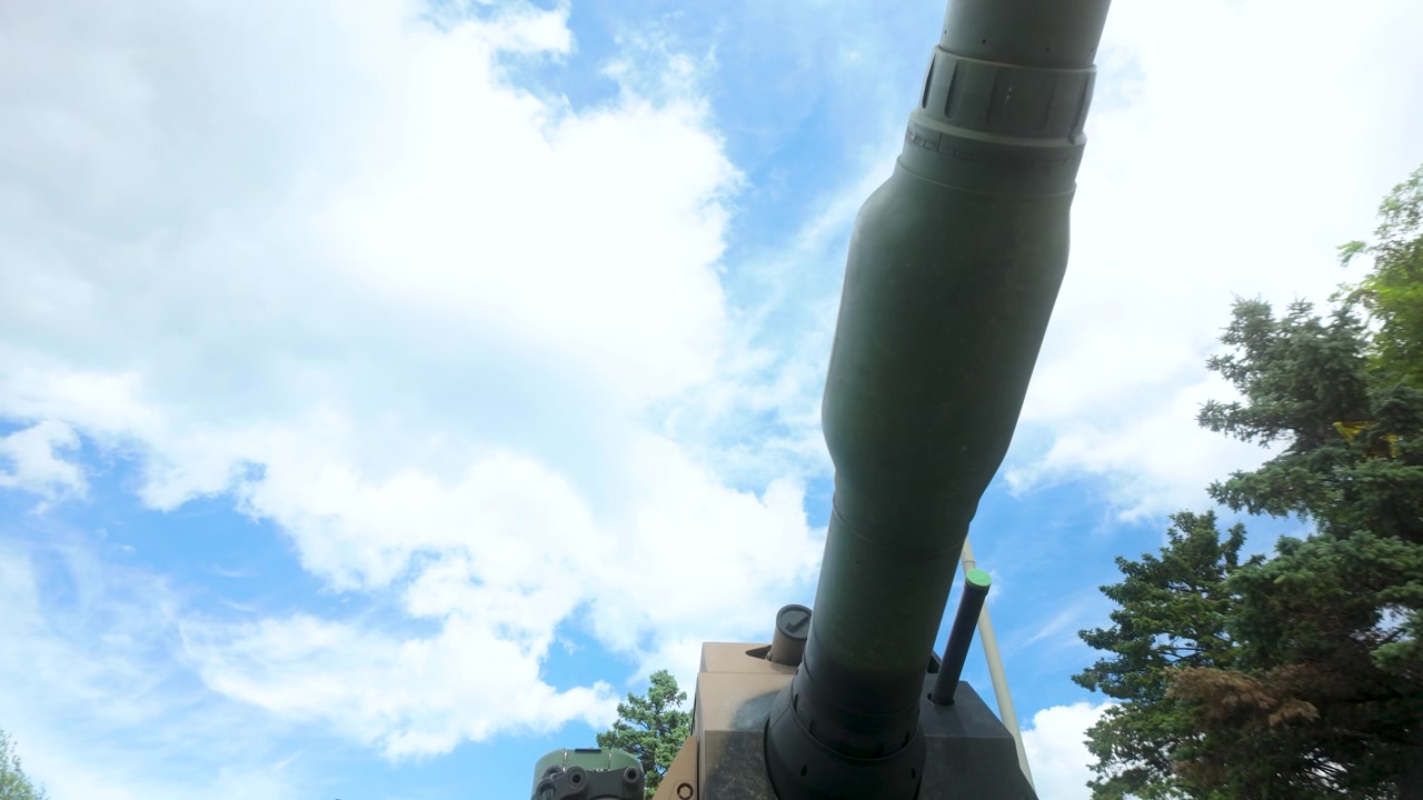 Inquadratura dal basso del cannone e della corazza della torretta di un moderno carro armato militare sotto un cielo luminoso. Utile per contenuti di difesa, storia e geopolitica