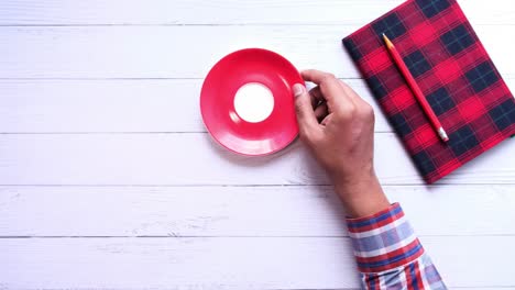 person holding a cup of tea on a wooden table