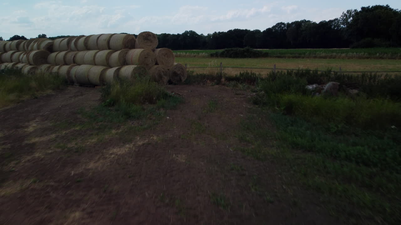 vuelo hacia un remolque abandonado y pacas de heno en un campo mientras la cámara se inclina hacia arriba