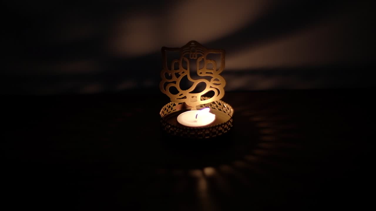 Closeup of shadow and light dance, play reflection on wall of Ganesha cutout, also Ganapati Vinayaka, one of the best-known and most worshipped deities in the Hindu pantheon, during Diwali