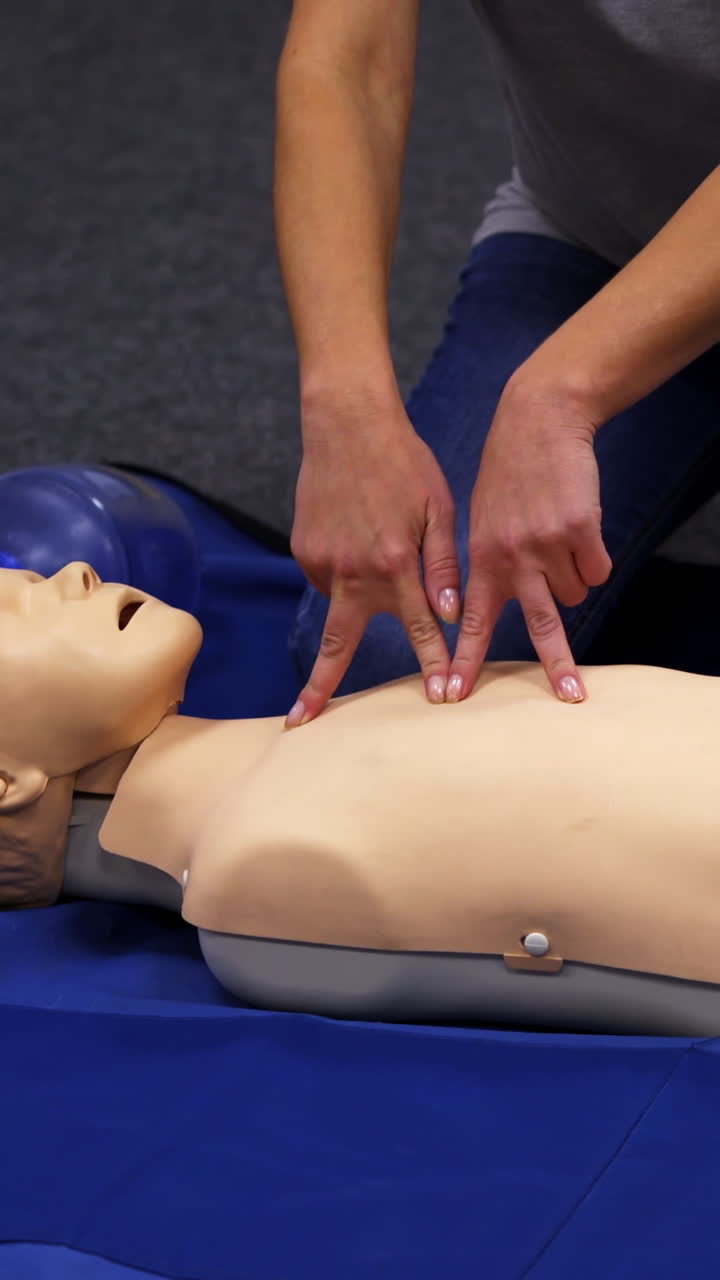 Giving first aid CPR on a dummy. Female trainer demonstrates cardiopulmonary reanimation. Training on a mannequin to save life. Vertical video