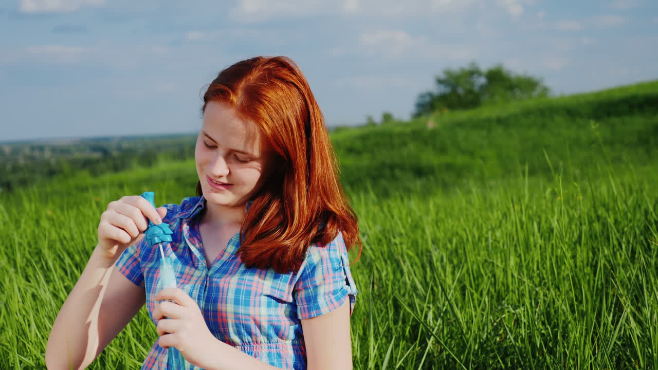 비누 거품을 가지고 노는 빨간 머리 십대 소녀