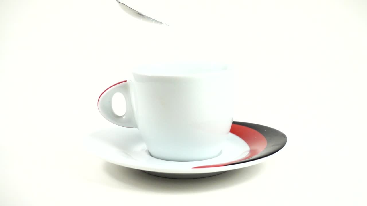 Dalla cucchiaio lo zucchero viene versato in una tazza. Movimento lento