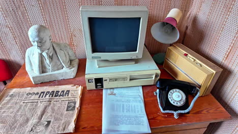 Vintage-desk-setup-with-old-computer,-rotary-phone,-and-Soviet-era-newspaper