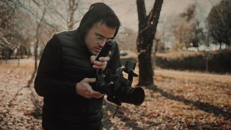 tracking shot of a young male filmmaker or videographer recording video footage out in nature