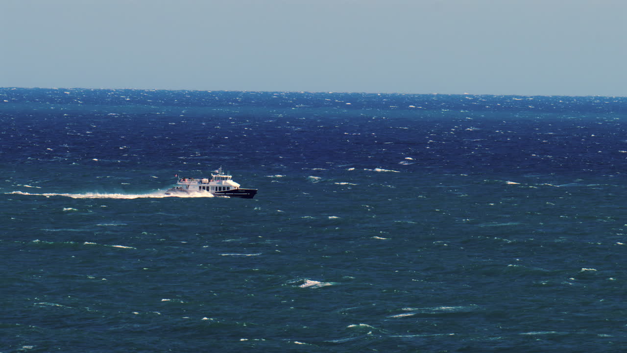 Nice, France - March 17, 2025: Distant view of a boat moving on the blue sea in daylight