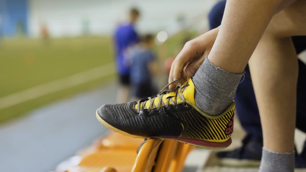 어린이 가 경기장 에서 축구 신발 을 고 있다