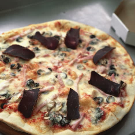 chef's hand adds spice to the pizza after cooking pizza in the kitchen of the restaurant. cooking food. sqare video