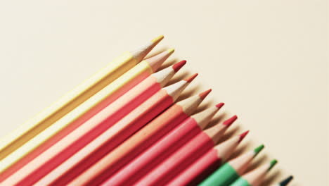 primer plano de lápices de colores dispuestos con espacio de copia sobre fondo beige, en cámara lenta