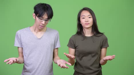young asian couple shrugging together
