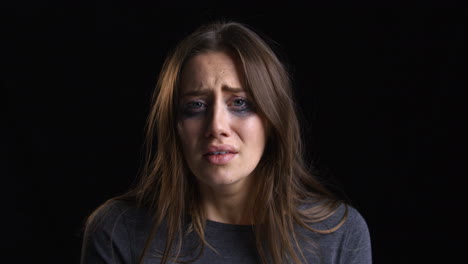 retrato de estudio de una mujer llorando con maquillaje manchado