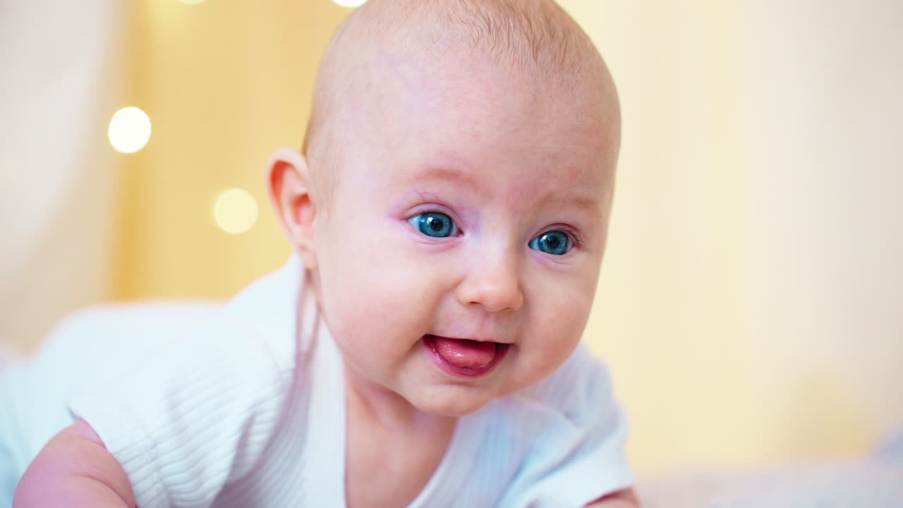 Süßes Baby mit blauen Augen lächelt und streckt die Zunge heraus