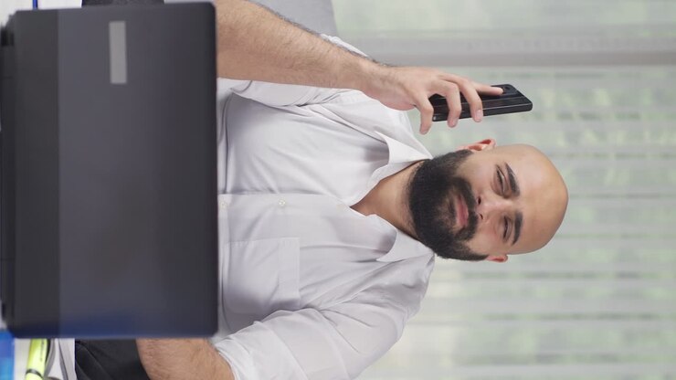 Vertical video of Home office worker man getting bad news on the phone.
