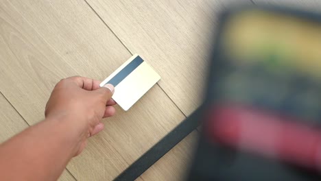 close-up of hand holding credit card next to laptop