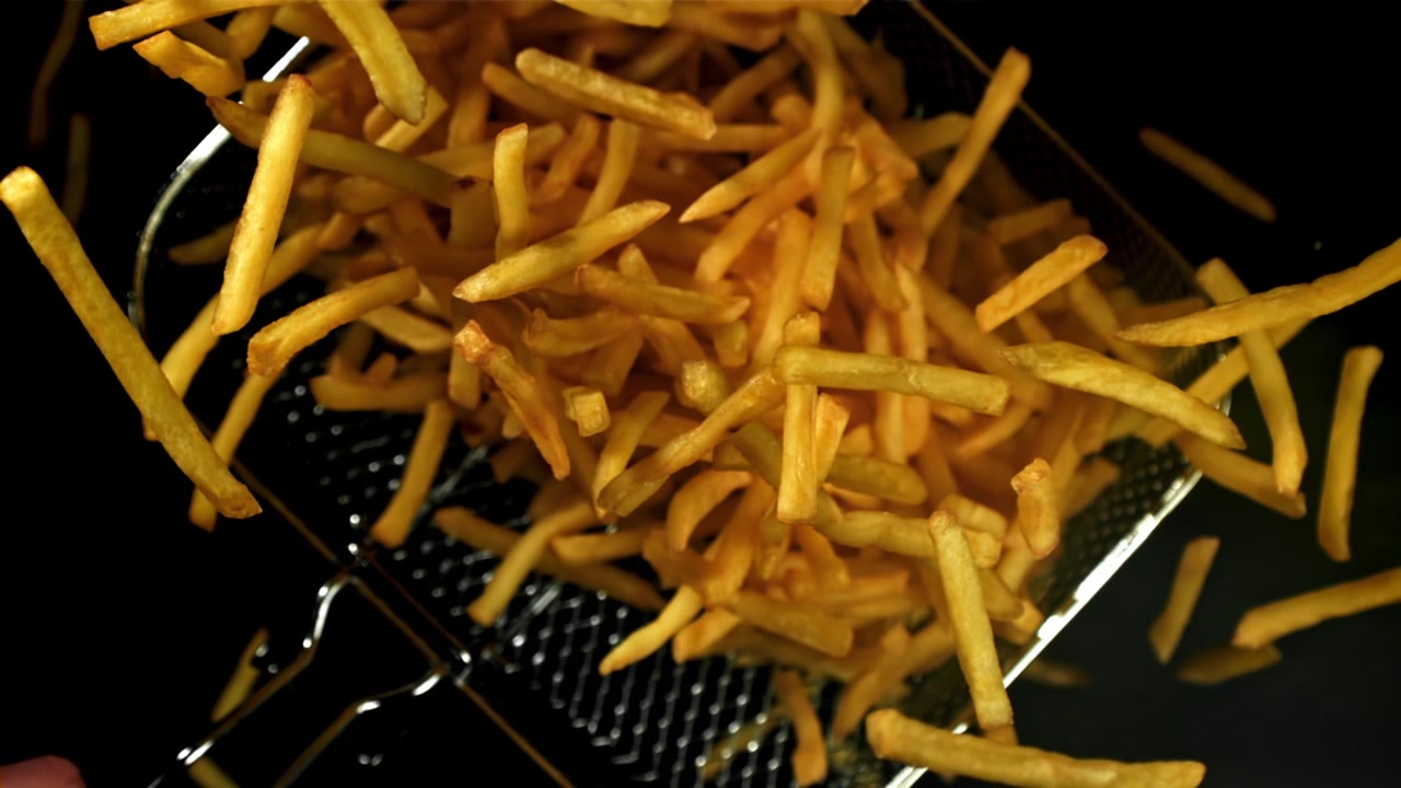 Golden French Fries Falling into a Fryer Basket in Slow Motion